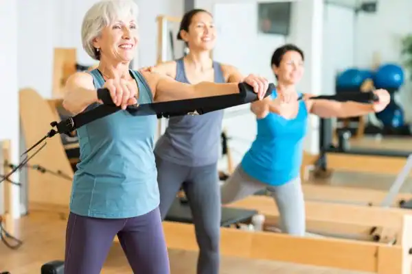 Toning Arms After 60: Empowering Womens Fitness Through Effective Weight Training 2 older woman doing weight training Gravesend and resistance in the gym to tone upper arms