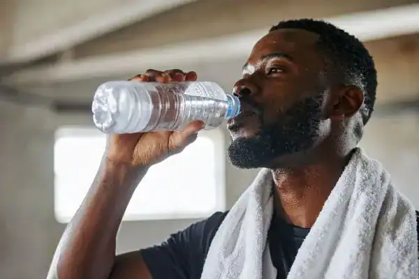 Image of man drinking water to improve hydration Gravesend after work out.